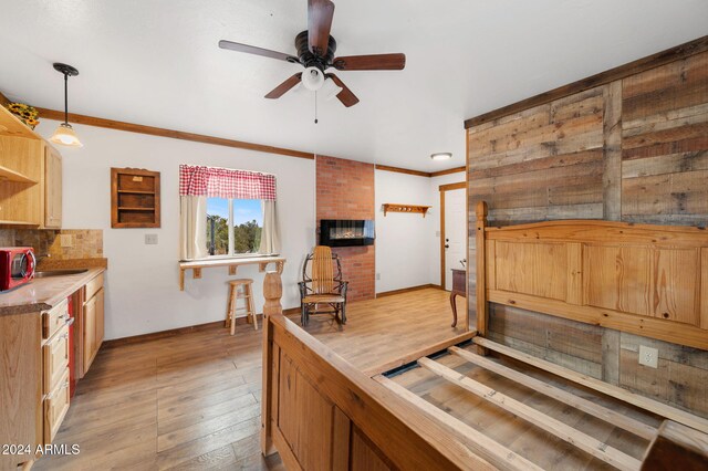 kitchen with ceiling fan, light hardwood / wood-style flooring, backsplash, decorative light fixtures, and ornamental molding