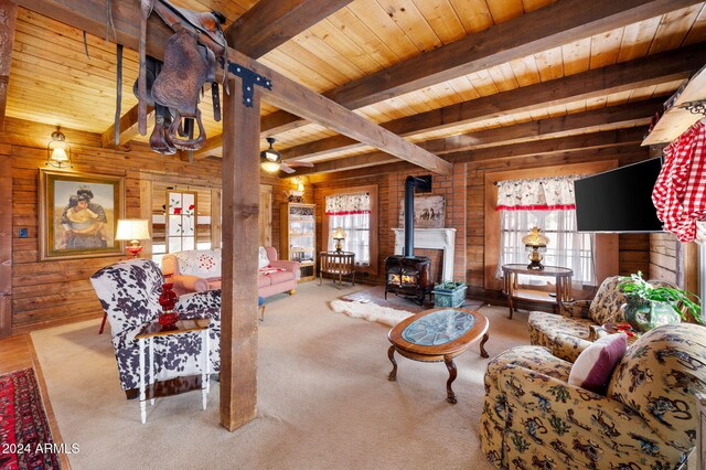 living room featuring beam ceiling, a wood stove, wood ceiling, and a healthy amount of sunlight