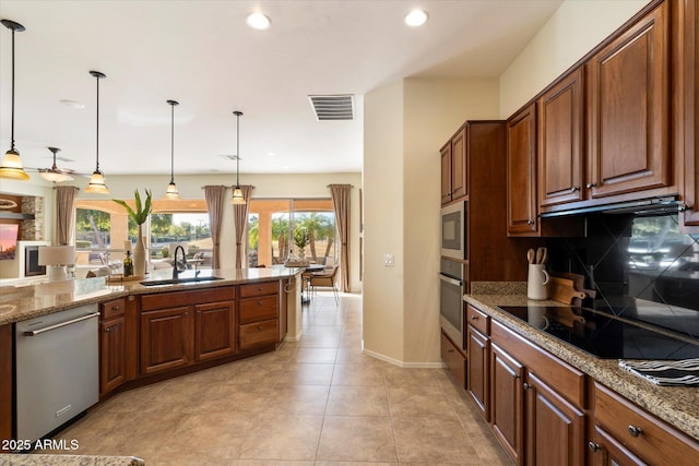 kitchen with tasteful backsplash, sink, hanging light fixtures, appliances with stainless steel finishes, and light stone counters