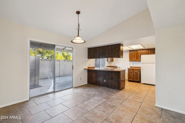 kitchen with vaulted ceiling, light tile patterned floors, white refrigerator, kitchen peninsula, and pendant lighting