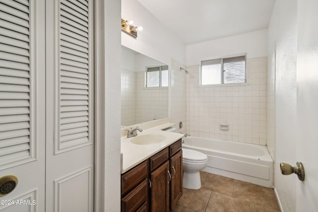 full bathroom with tile patterned flooring, vanity, tiled shower / bath, and toilet