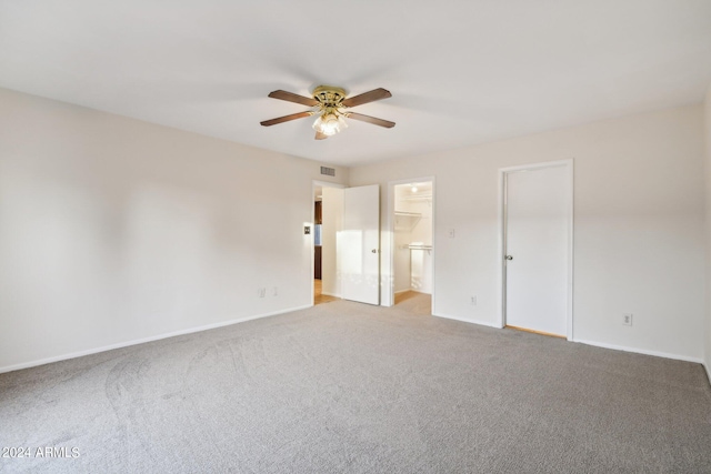 unfurnished bedroom featuring ceiling fan, light carpet, and ensuite bath