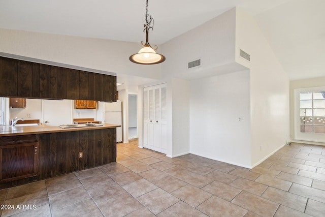 kitchen featuring pendant lighting, sink, white fridge, light tile patterned floors, and dark brown cabinetry