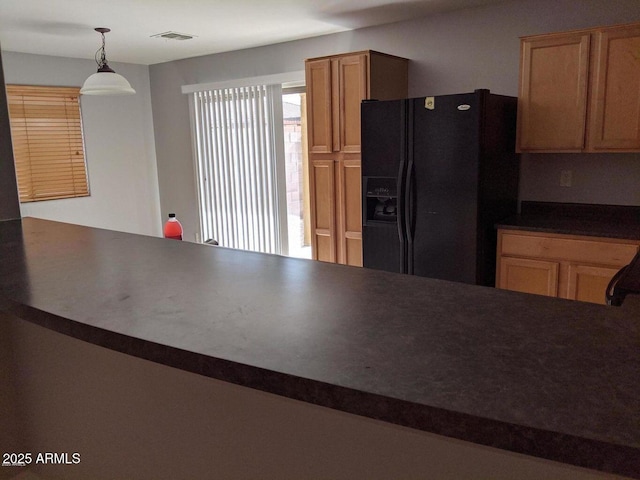 kitchen featuring black refrigerator with ice dispenser, dark countertops, visible vents, and decorative light fixtures