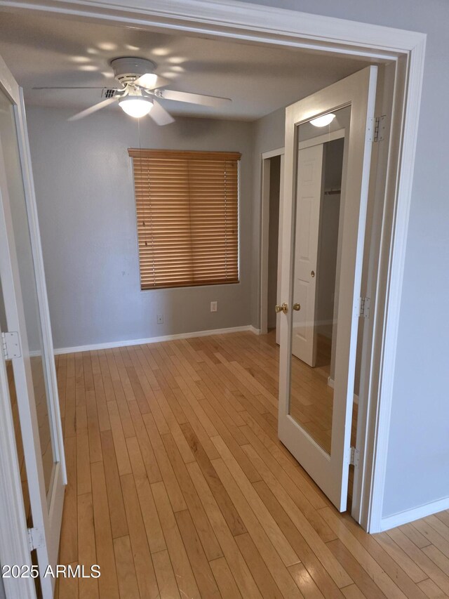 unfurnished room featuring light wood-style floors, baseboards, and a ceiling fan