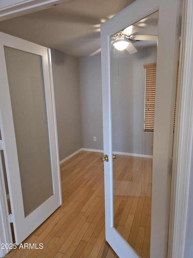 interior space featuring light wood finished floors, baseboards, and ceiling fan