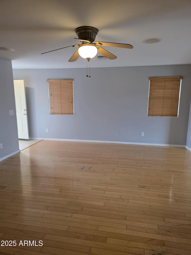spare room with ceiling fan, baseboards, visible vents, and wood finished floors
