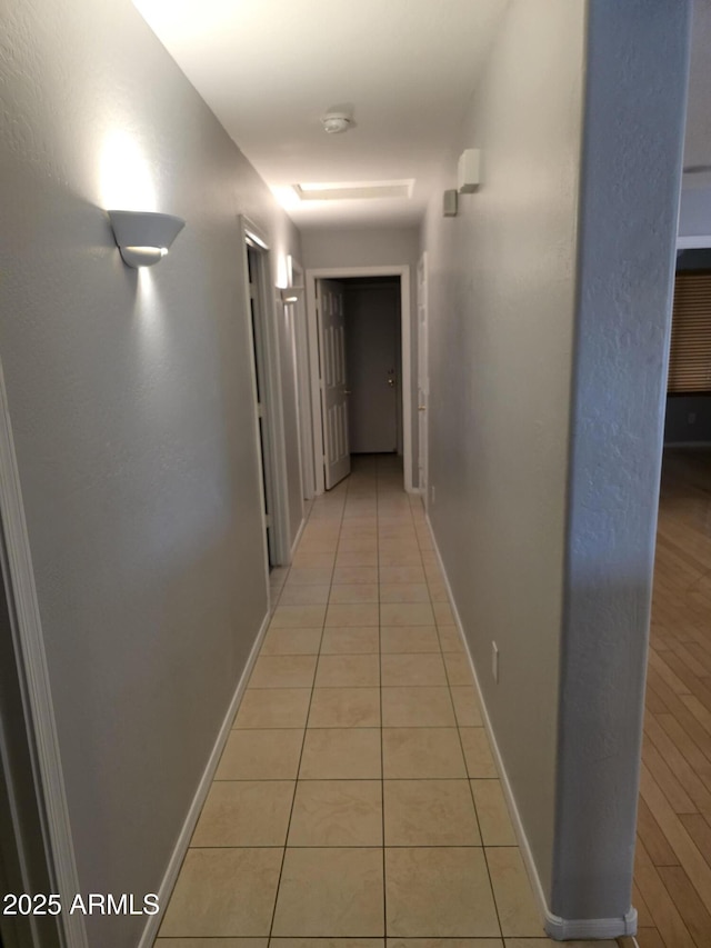 hallway featuring light tile patterned floors and baseboards