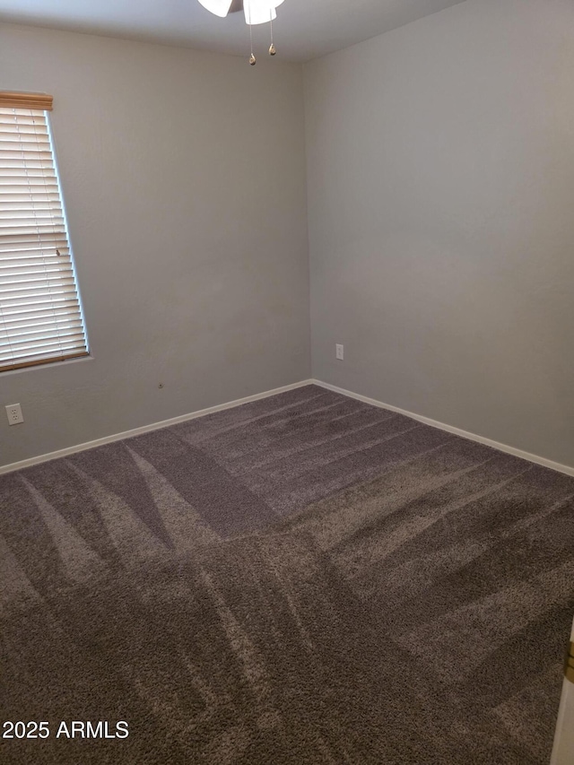 unfurnished room with dark colored carpet, baseboards, and a ceiling fan