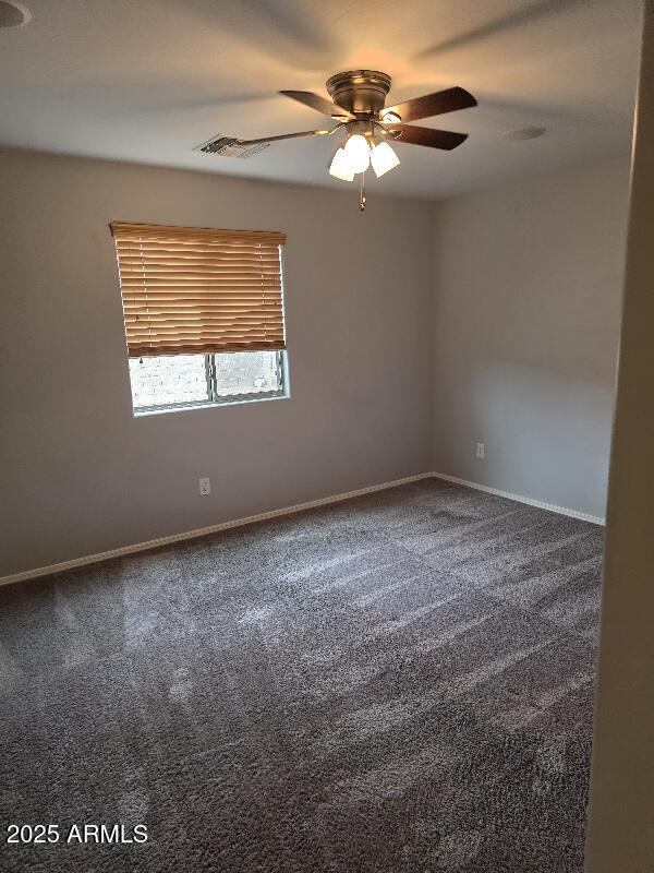 spare room with baseboards, visible vents, ceiling fan, and carpet floors