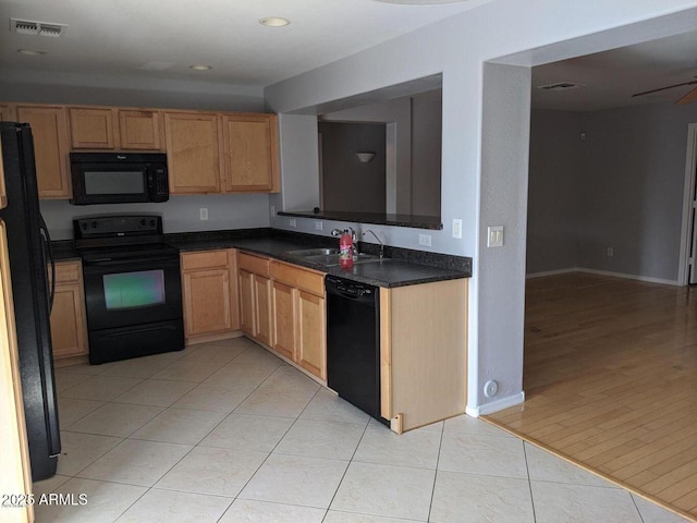 kitchen with light tile patterned floors, dark countertops, visible vents, a sink, and black appliances