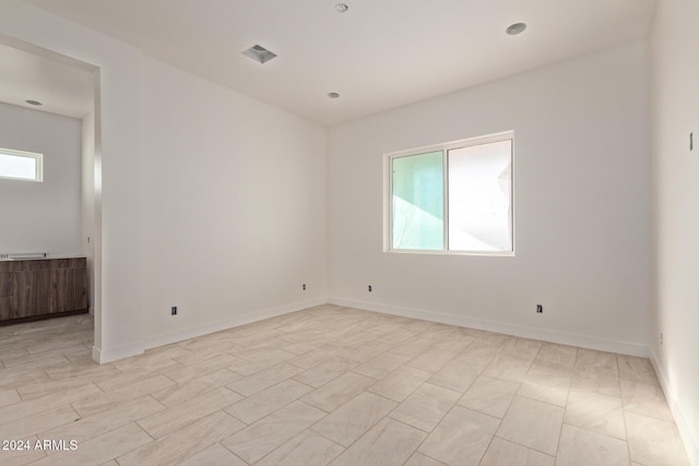 spare room with visible vents, plenty of natural light, and baseboards