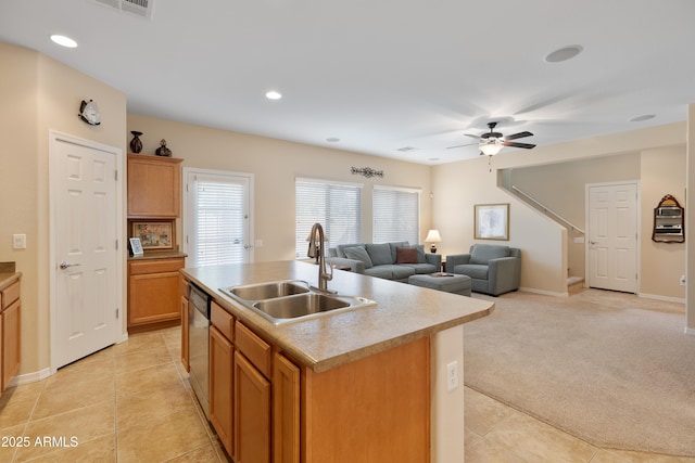 kitchen featuring sink, light colored carpet, ceiling fan, a center island with sink, and stainless steel dishwasher