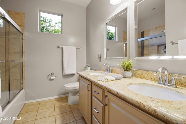 full bathroom with tile patterned flooring, vanity, bath / shower combo with glass door, and toilet