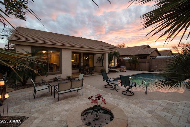 pool at dusk with a patio and an outdoor fire pit