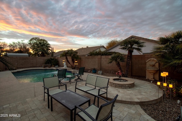 pool at dusk with a patio and a fire pit