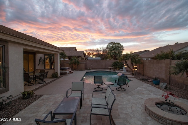 pool at dusk with an outdoor fire pit and a patio