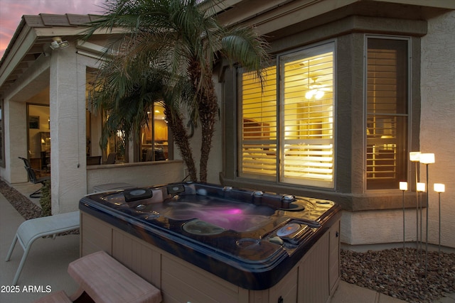 patio terrace at dusk featuring a hot tub