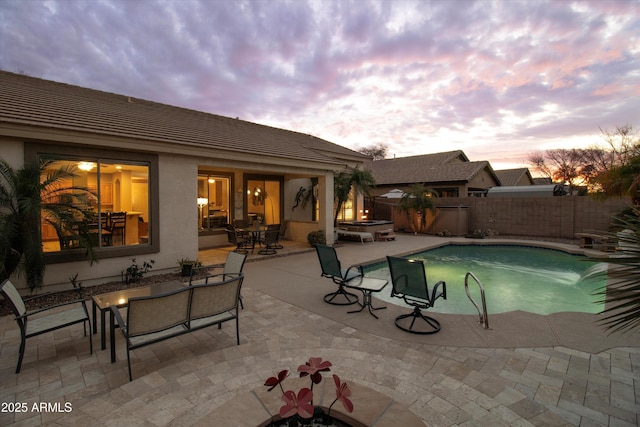 pool at dusk with a patio area