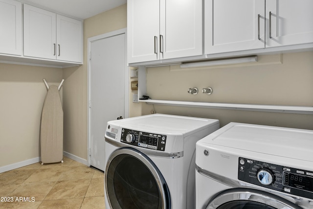 washroom with light tile flooring, washing machine and clothes dryer, and cabinets