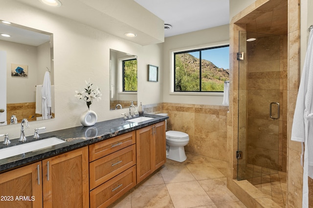 bathroom featuring tile walls, walk in shower, toilet, double sink vanity, and tile floors