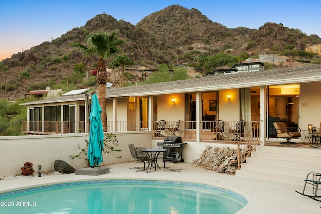 back house at dusk featuring a mountain view and a patio area