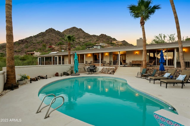 pool at dusk with a patio area and a mountain view