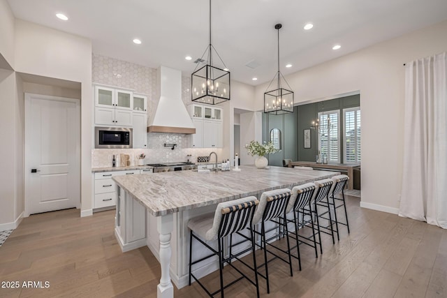 3814 W Running Deer Trl, Phoenix, AZ 85083 - kitchen featuring custom exhaust hood, stainless steel microwave, light wood-type flooring, a spacious island, and recessed lighting