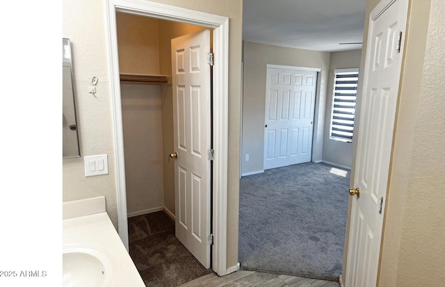 bathroom with baseboards, a textured wall, and vanity