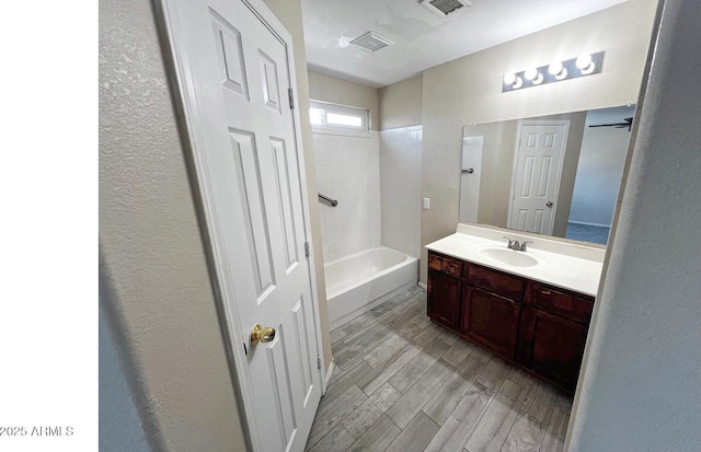 bathroom featuring a textured wall, visible vents, wood finished floors, and vanity