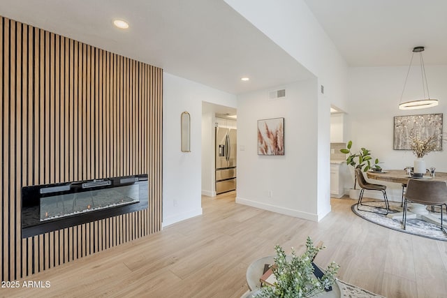 living area featuring light wood finished floors, visible vents, and baseboards