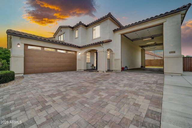 19026 W Becker Ln, Surprise, AZ 85388 - mediterranean / spanish home featuring a tile roof, a garage, stucco siding, decorative driveway, and fence