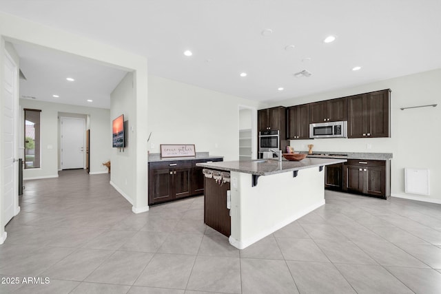 19026 W Becker Ln, Surprise, AZ 85388 - kitchen with stainless steel appliances, a breakfast bar, dark brown cabinetry, light tile patterned floors, and recessed lighting