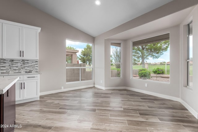 unfurnished dining area featuring light hardwood / wood-style flooring and lofted ceiling