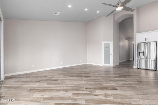 unfurnished living room with ceiling fan and a high ceiling