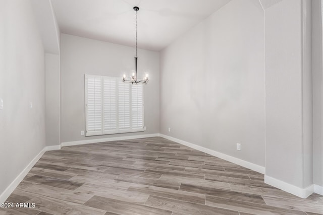 unfurnished dining area with hardwood / wood-style flooring and an inviting chandelier