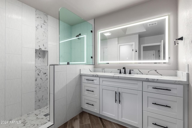 bathroom with tiled shower, wood-type flooring, and vanity