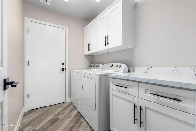 clothes washing area with cabinets, separate washer and dryer, and light wood-type flooring