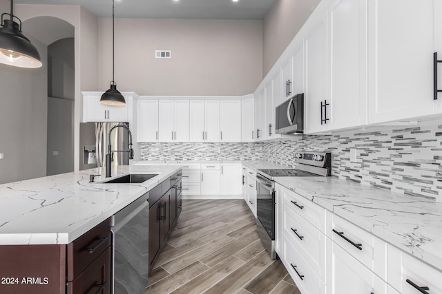 kitchen featuring white cabinetry, hanging light fixtures, an island with sink, and stainless steel appliances