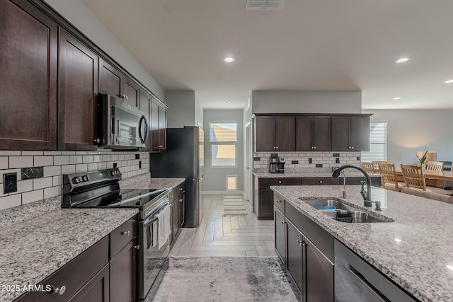 9454 E Alfalfa Dr, Florence, AZ 85132 - kitchen with stainless steel appliances, a sink, dark brown cabinetry, decorative backsplash, and light stone countertops