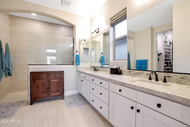 bathroom with tiled shower, vanity, and tile patterned floors