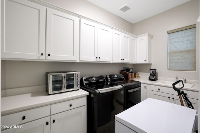 laundry room with sink, washing machine and dryer, and cabinets