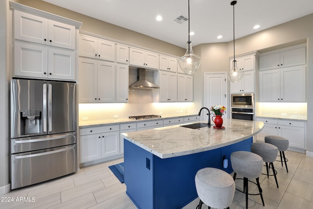 kitchen with appliances with stainless steel finishes, wall chimney range hood, sink, and white cabinets