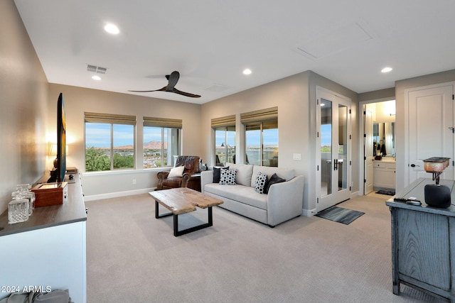 carpeted living room with ceiling fan and french doors