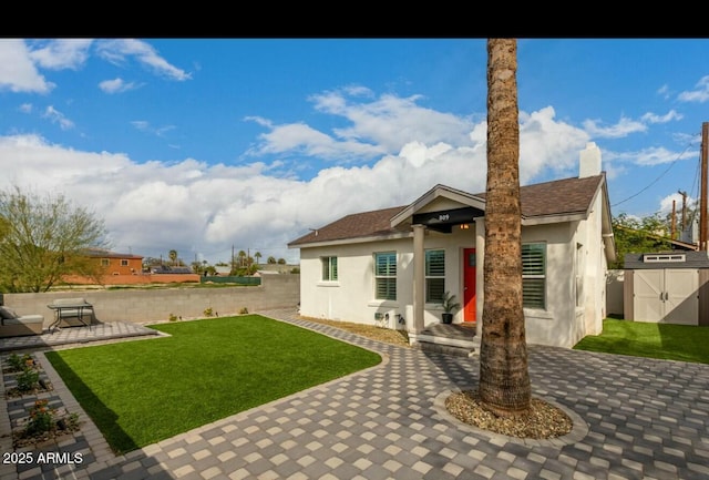 back of house featuring a patio area, a shed, and a lawn