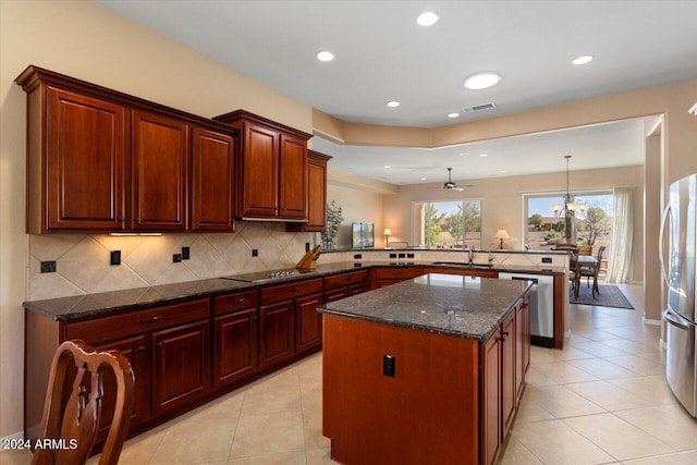 kitchen featuring appliances with stainless steel finishes, sink, a kitchen island, kitchen peninsula, and backsplash