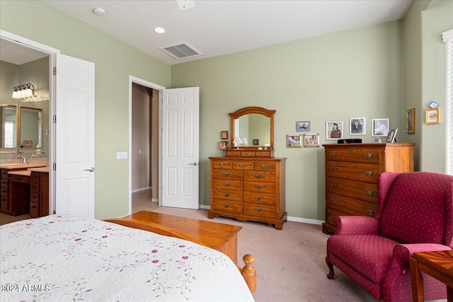 bedroom with ensuite bathroom and light carpet