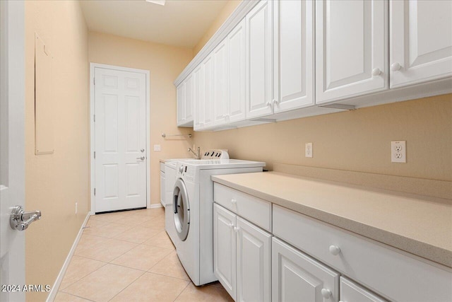 clothes washing area with light tile patterned floors, cabinets, and washer and dryer