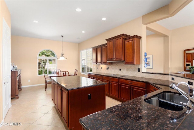 kitchen with sink, backsplash, a center island, and dark stone countertops