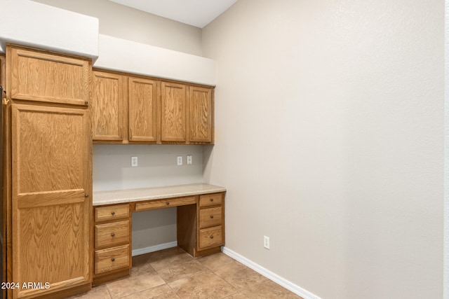 unfurnished office with light tile patterned flooring and built in desk